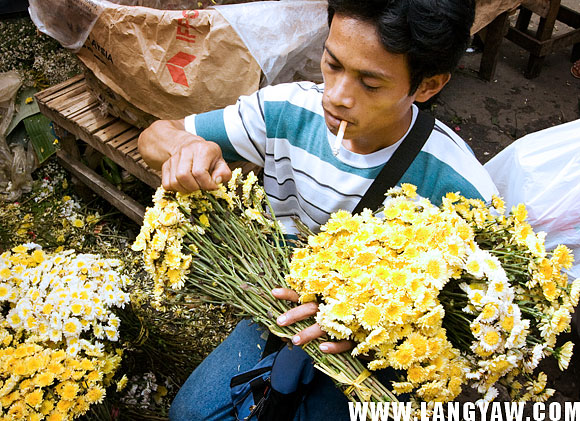 A male flower vendor prepares a bouquet, usually by the dozen, at the streetside Carbon market.