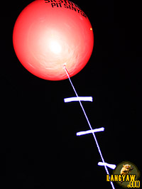 Rolled papers bearing the prayers of the devotee are tied to a balloon which will then be released when the image passes during the procession.