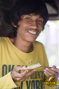 A man happily posing after taking a bite of the kakanin