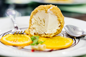 Deep fried ice cream showing cross section. Vanilla ice cream inside, layer of fried cookie crumb outside