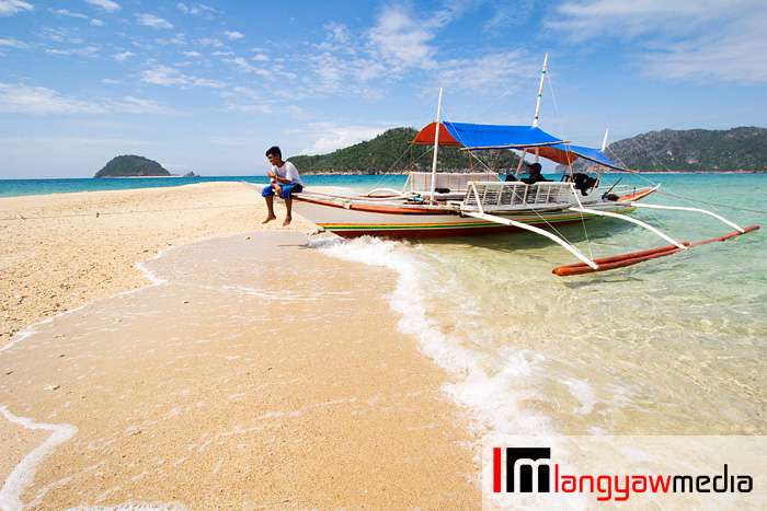 Motorized outrigger boat (banca) docked at the sand.