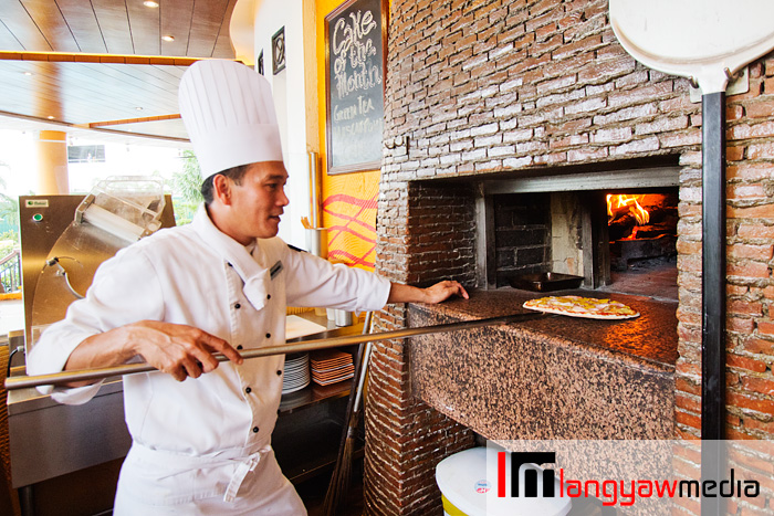 The chef readying a pizza at the mango wood fired oven