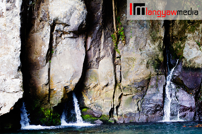 The rock wall within the waterfall area with water streaming down 