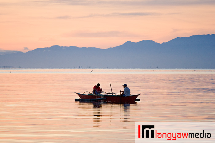 Beautiful morning hue paint the sky before sunrise as two fishermen on their banca in Ormoc City