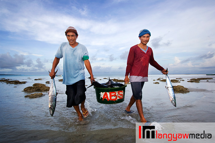 Fishermen carrying fresh catch in the morning off the beach of Cuyo town in Palawan