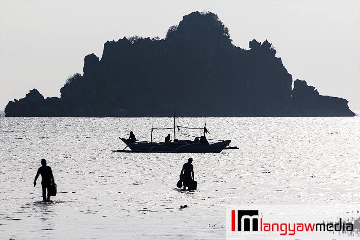 Silhouettes of fishermen, banca and an islet off the coast of Isla Gigantes Norte in Carles, Iloilo