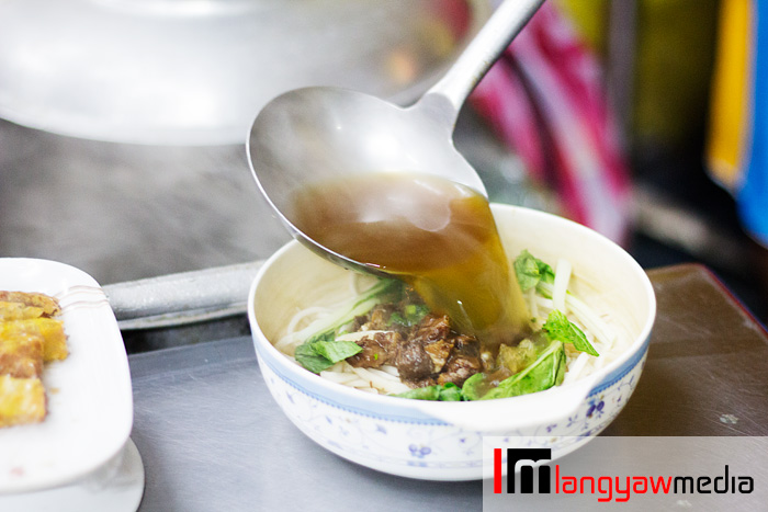 An order of beef noodle soup being readied