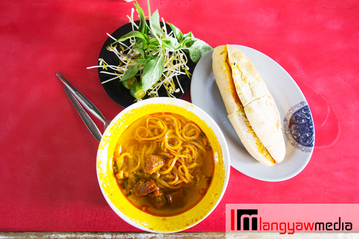 An order of beef stew noodles, pork french bread and a side dish of mung bean sprouts, calamansi and basil leaves