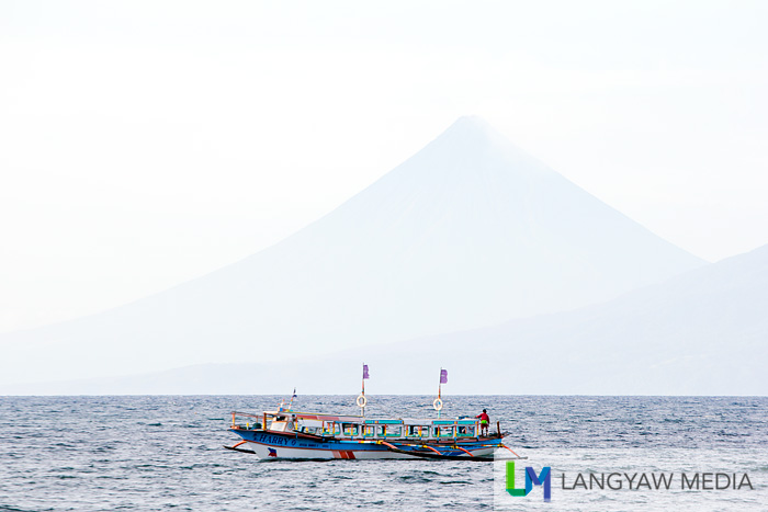 Beautiful Mt. Mayon in the distance as an outrigger boat passes by Sabang