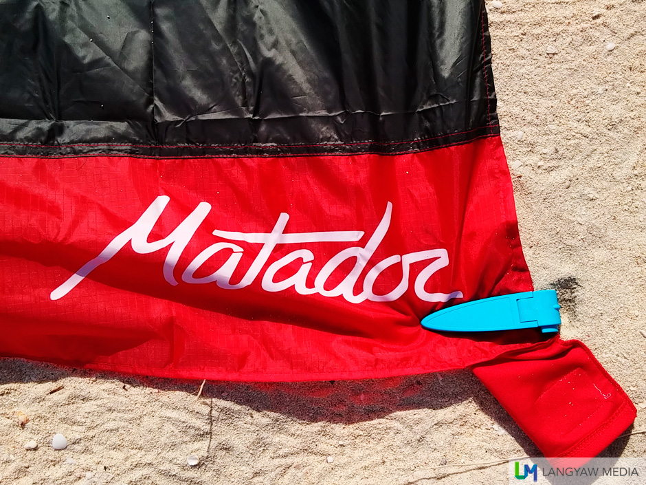 The Matador pocket towel held down by a beach blanket clip