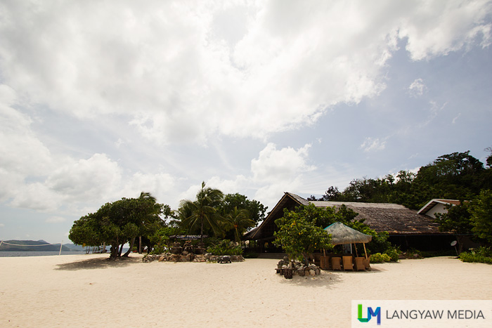 The low buildings surrounded with trees, vegetation, white sand and the eternally aquamarine waters of the sea
