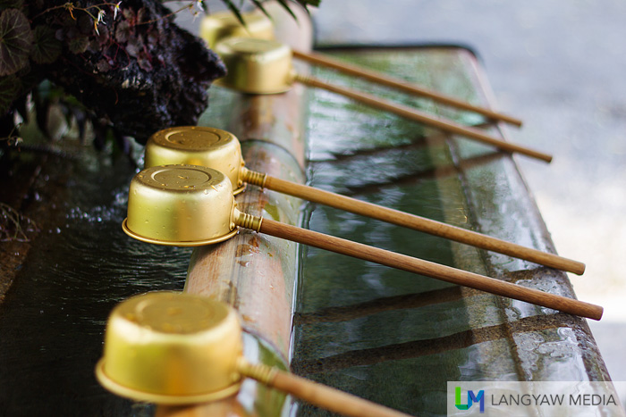 Steel ladles with wooden handles at the chozuya where the Buddhist water purification rite temizu  is performed. It;s located just a few meters from the main entrance of the temple.