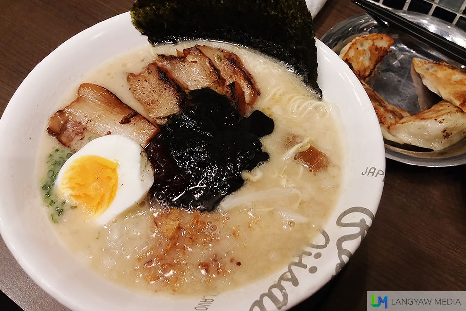 Roast pork ramen black is a soy based soup with stock from long simmered pork bones. It also has menma (simmered bamboo shoots), a piece of nori (seaweed) sheet, moyashi (bean sprouts), a half of tamago (sticky yolk egg) and a black sauce from roasted sesame seeds