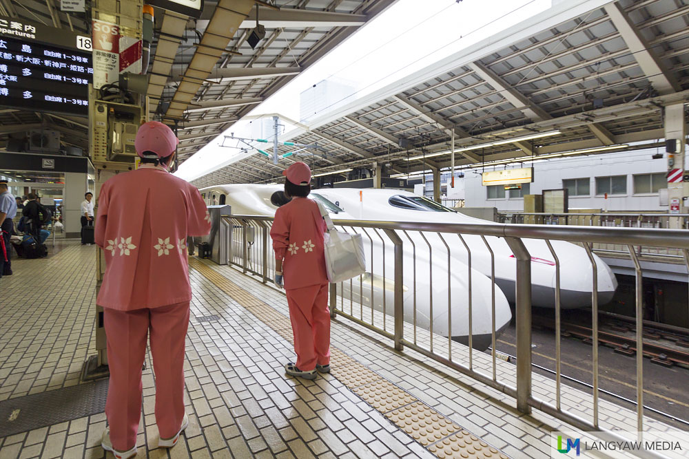 Cleaning crew in sakura pink uniform waiting for the train to stop
